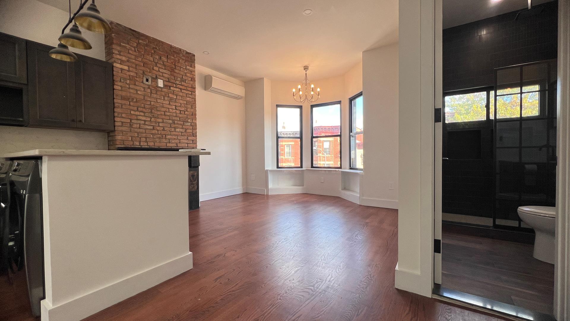 a view of an empty room with a window and wooden floor