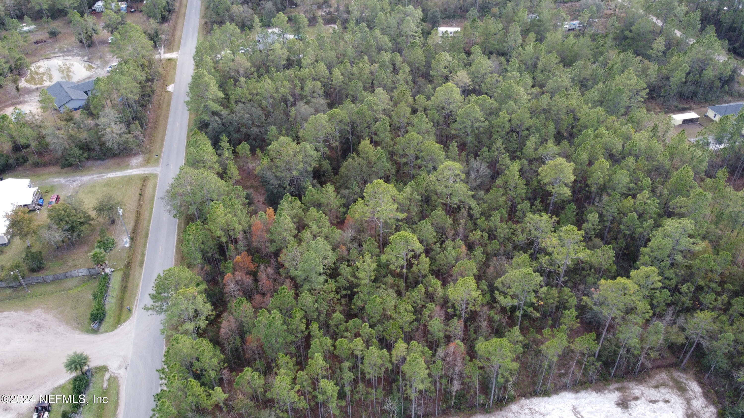 an aerial view of residential houses with outdoor space and trees