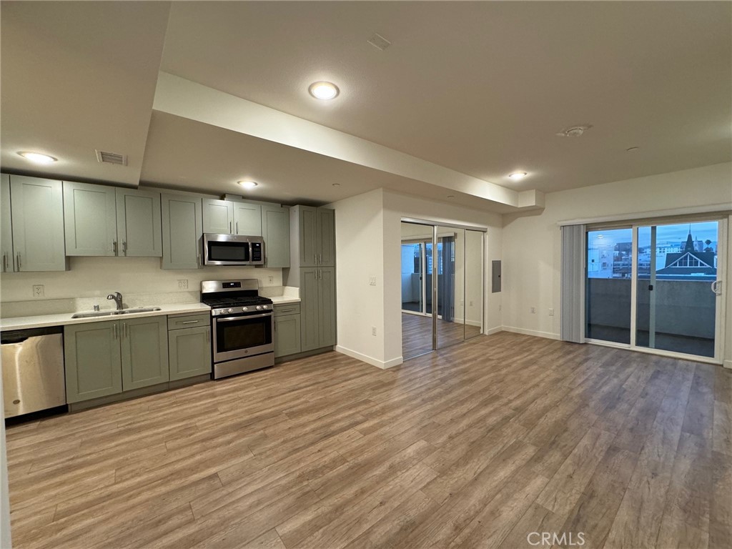 a large kitchen with stainless steel appliances granite countertop a stove and a wooden floors