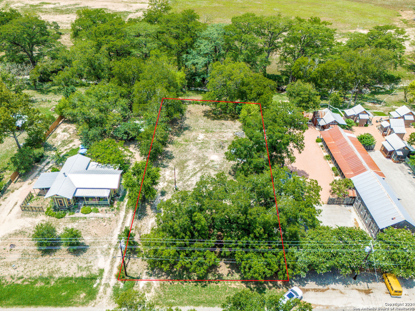 an aerial view of residential houses with outdoor space and trees all around