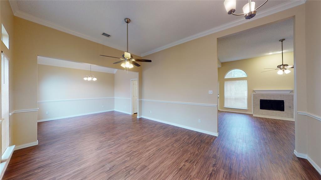 a view of a livingroom with wooden floor a ceiling fan and kitchen space