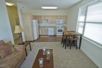 a living room with furniture and a dining table next to a window