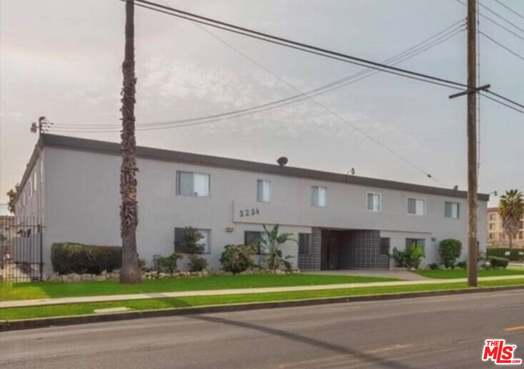 a front view of a building with a yard and plants