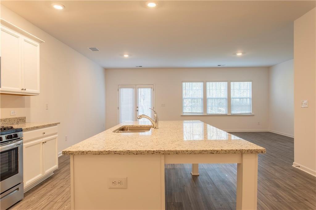 a kitchen with granite countertop a sink a stove and dishwasher with wooden floor