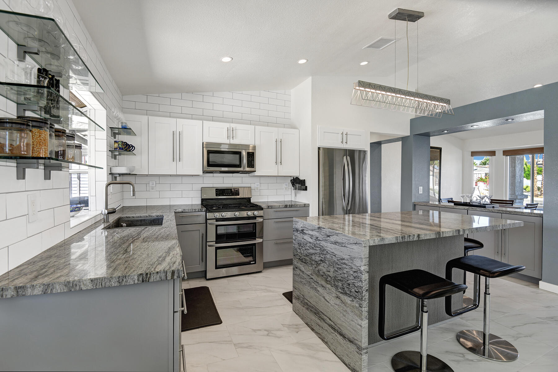 a kitchen with kitchen island granite countertop a stove top oven a sink a counter space and cabinets