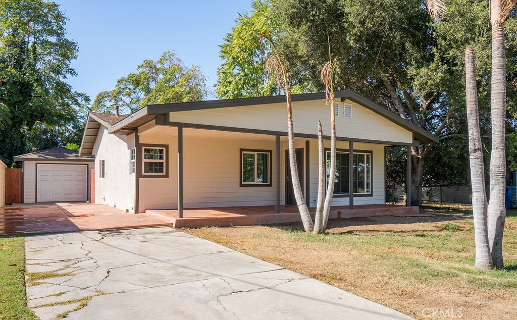 a view of a house with small yard plants and large tree