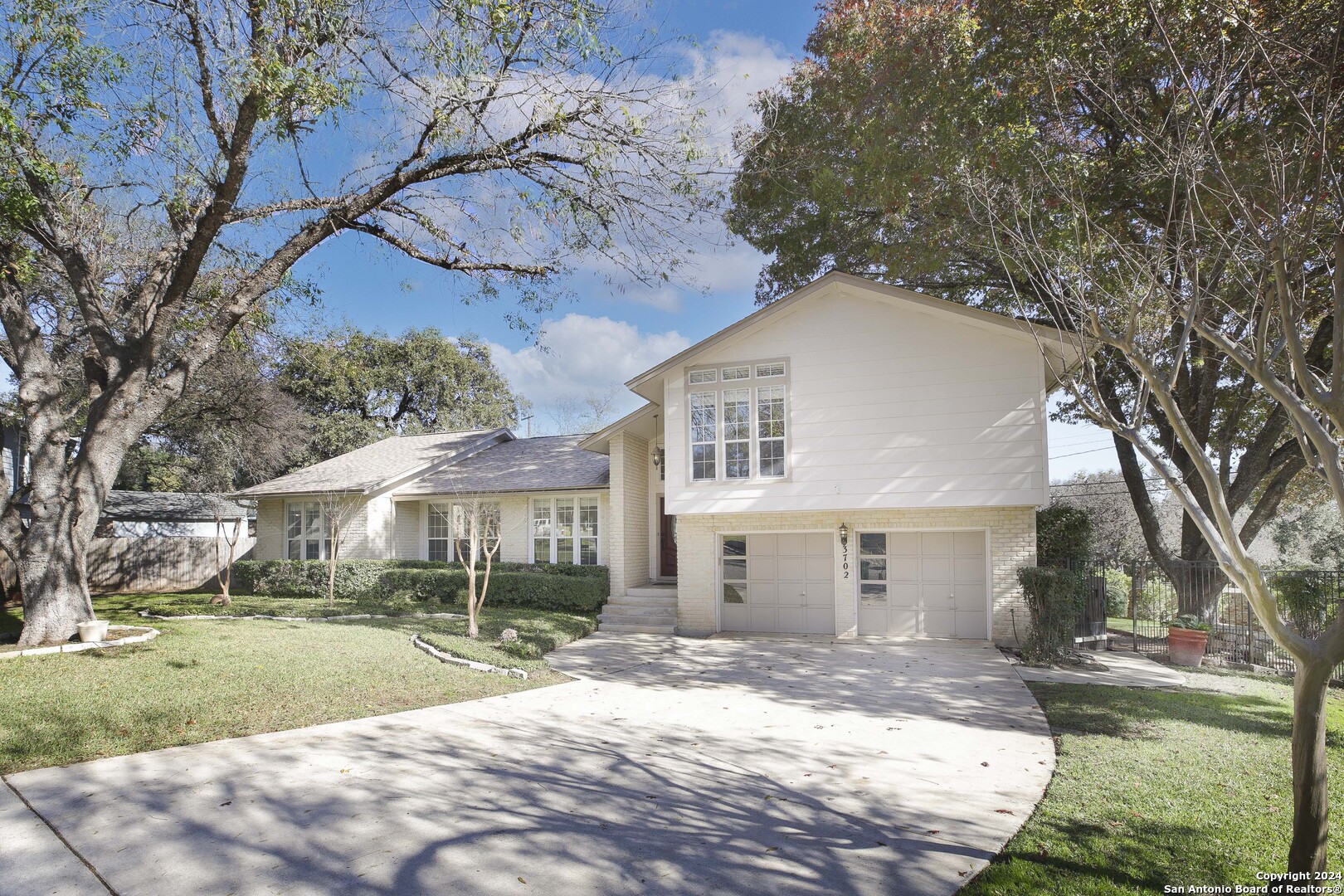 a view of a white house with a yard and large tree