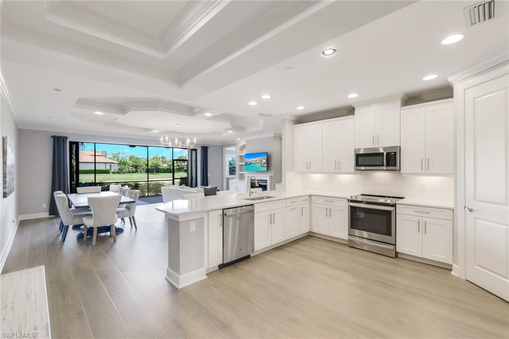 a large white kitchen with lots of white cabinets a sink a dining table and chairs