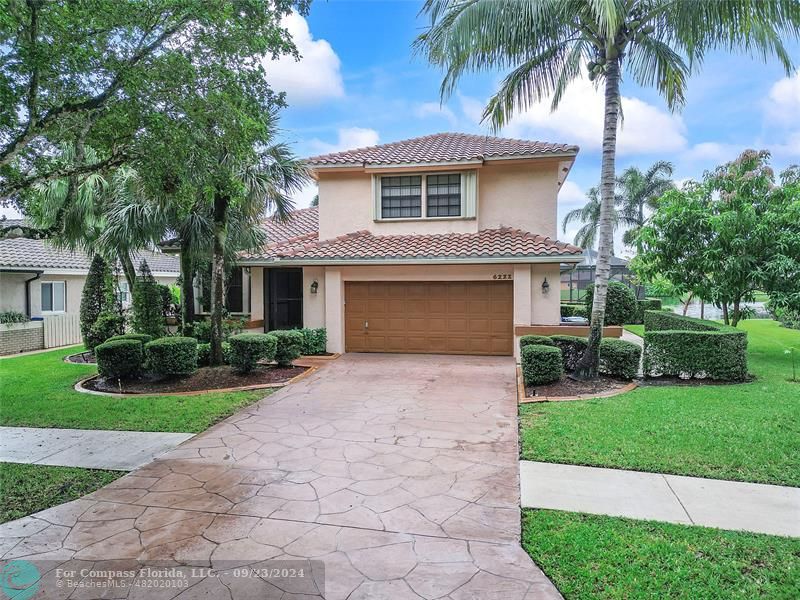 a front view of a house with a garden and palm trees