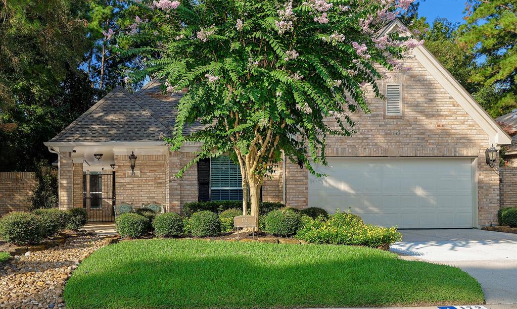 a view of a white house next to a yard with plants and trees