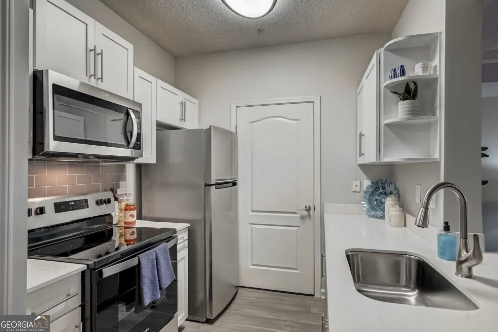 a kitchen with stainless steel appliances a refrigerator sink and microwave