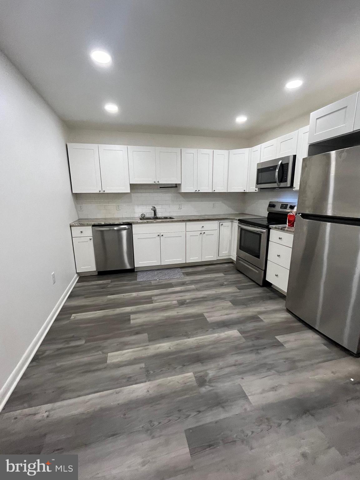 a kitchen with a refrigerator a stove top oven a sink and cabinets