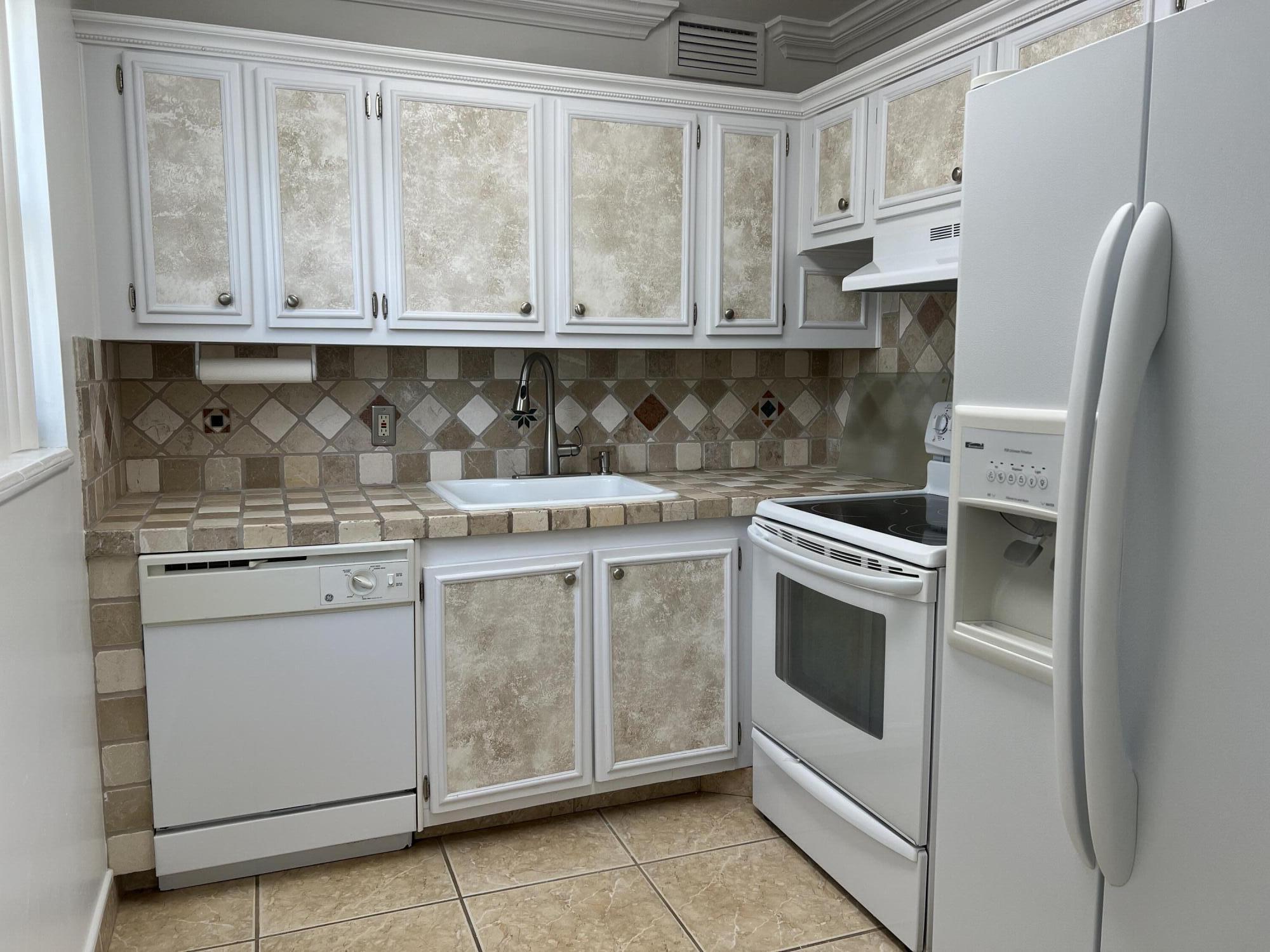 a kitchen with stainless steel appliances granite countertop white cabinets a refrigerator and a stove