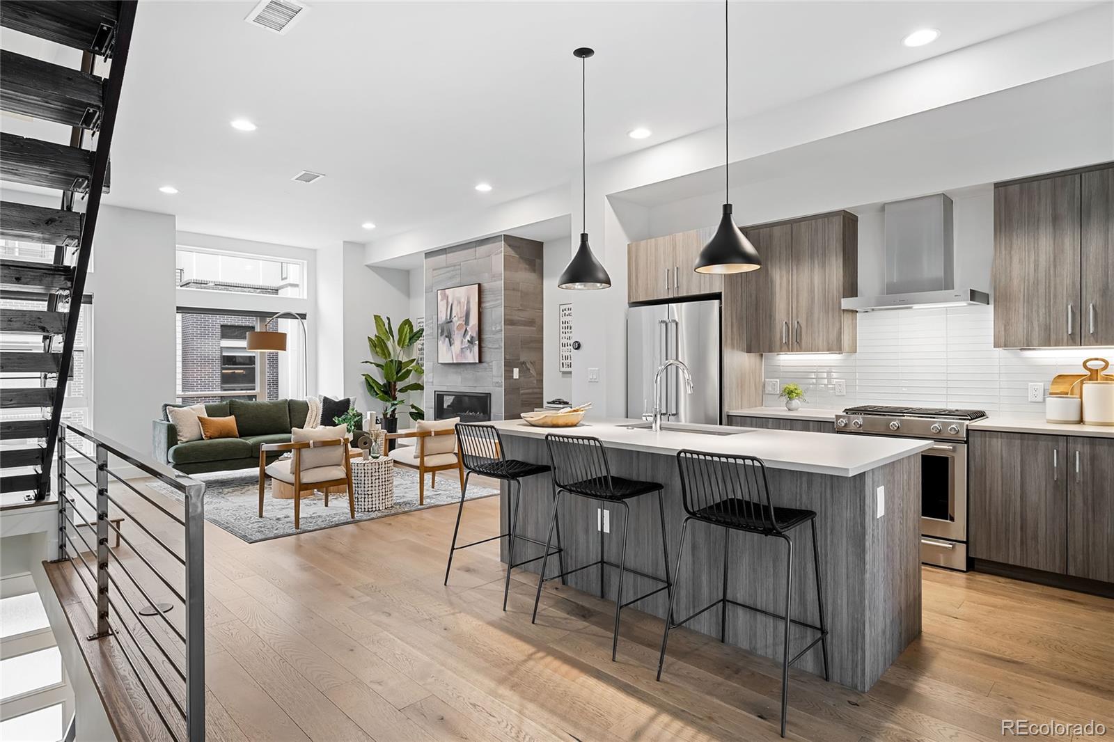 a kitchen with stainless steel appliances a stove center island wooden floor and living room view