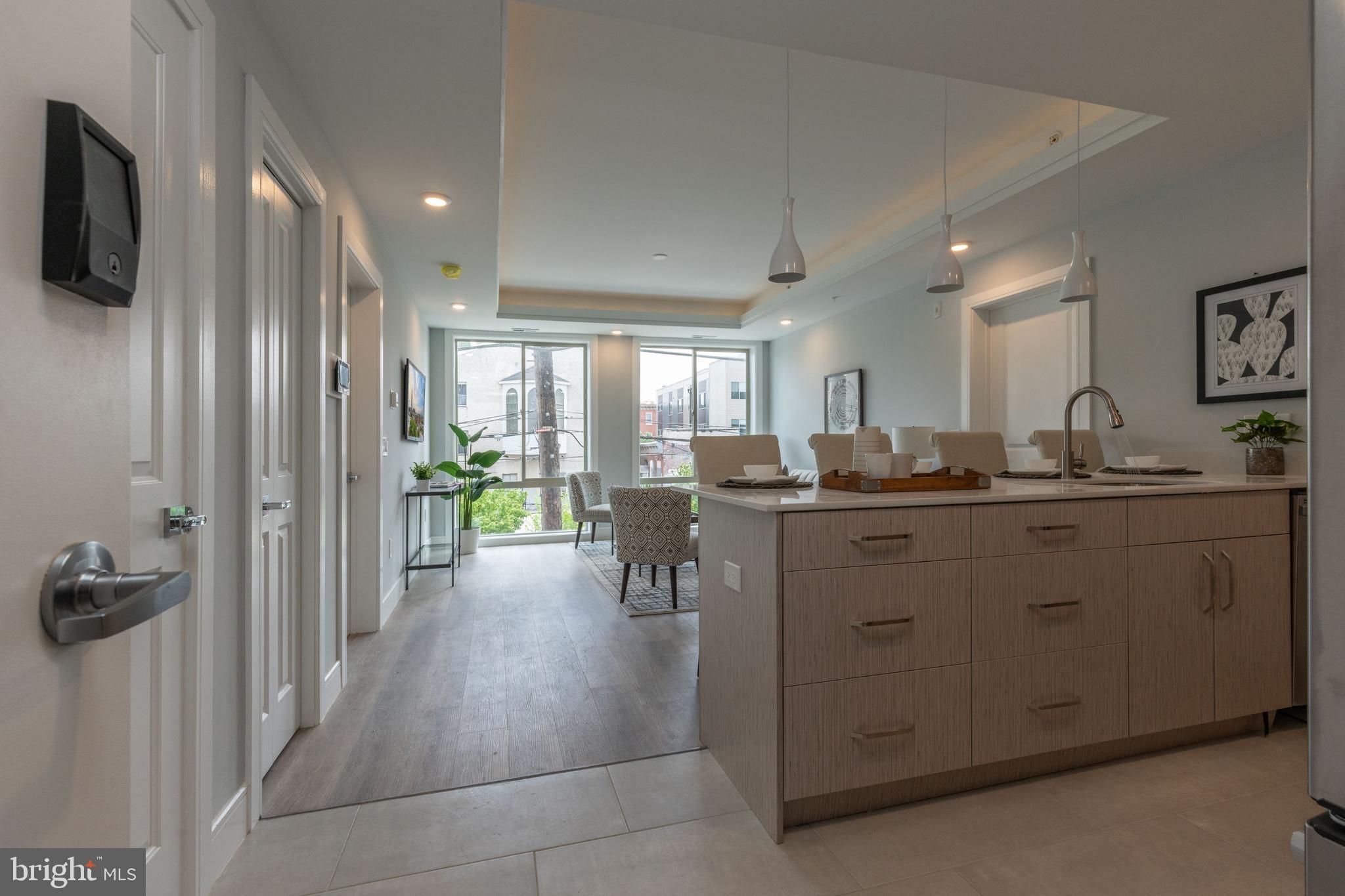 a kitchen with kitchen island a counter top space a sink a refrigerator and a view of living room