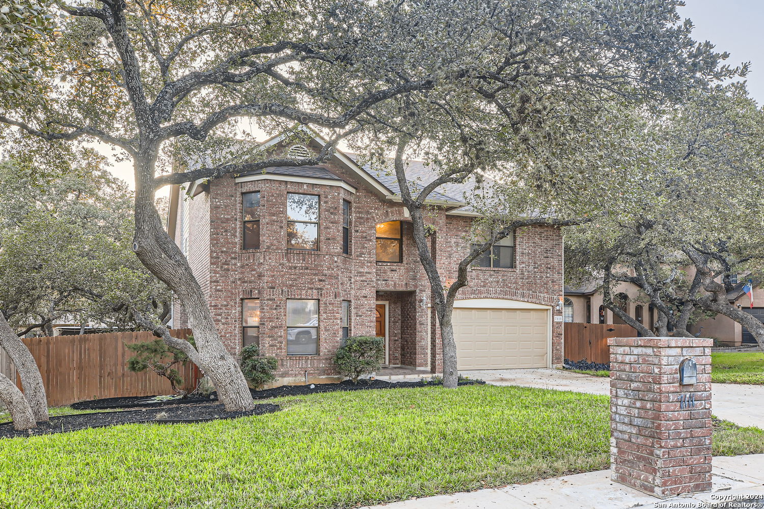 a front view of a house with a yard and tree