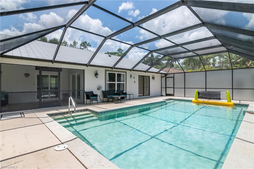 View of swimming pool featuring glass enclosure, an outdoor hangout area, and a patio area