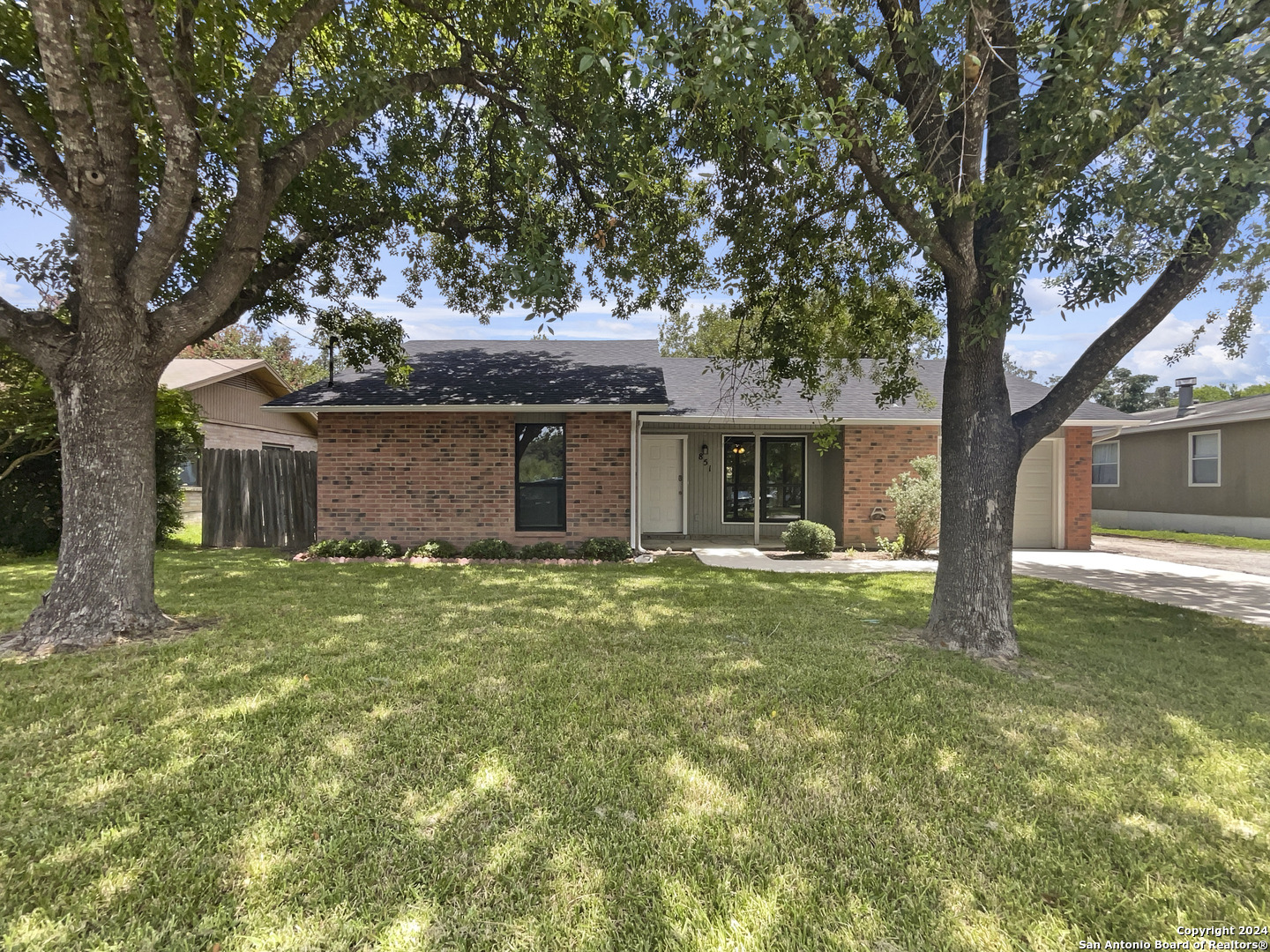 a backyard of a house with table and chairs and large tree