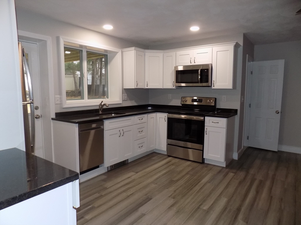 a kitchen with stainless steel appliances granite countertop a stove a sink and a microwave