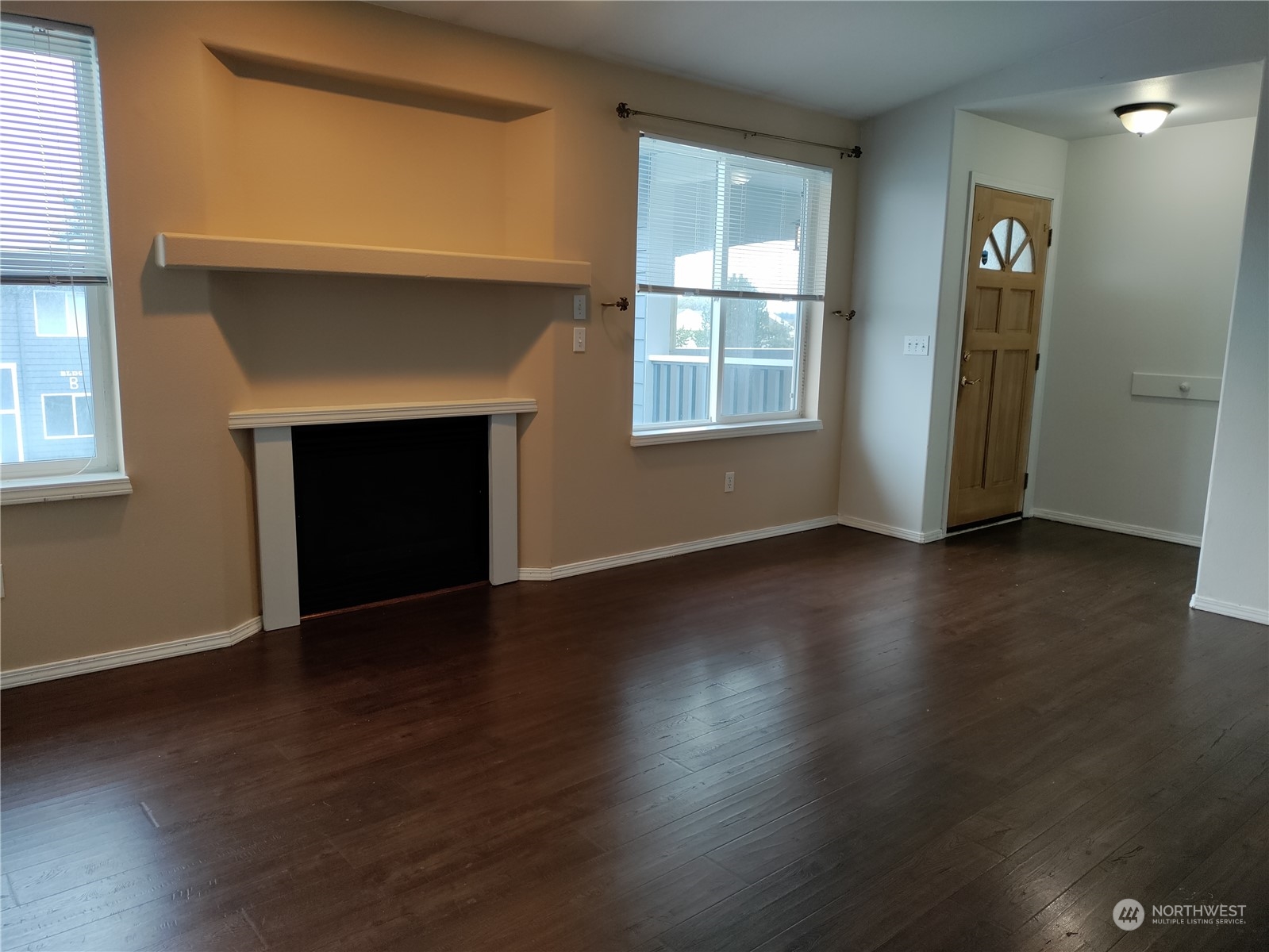 an empty room with wooden floor a fireplace and windows