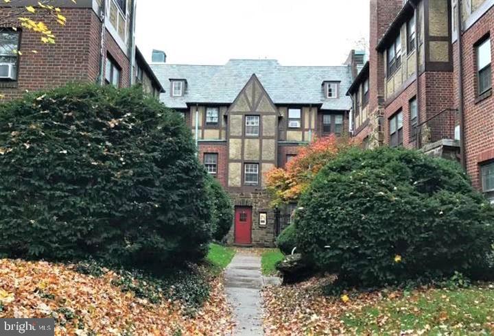 a view of a brick house next to a yard with plants and trees