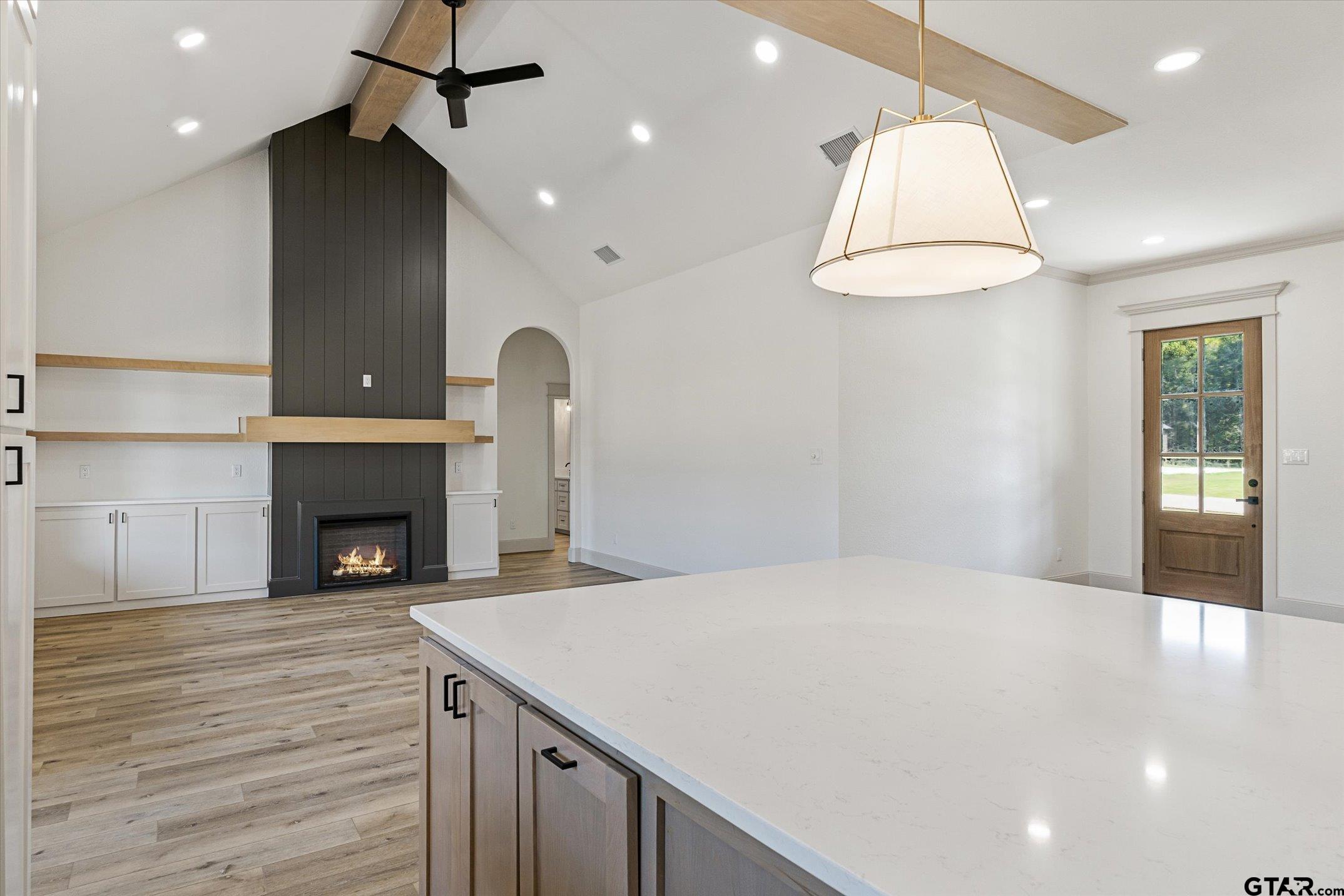 a view of an empty room with a fireplace and a chandelier fan