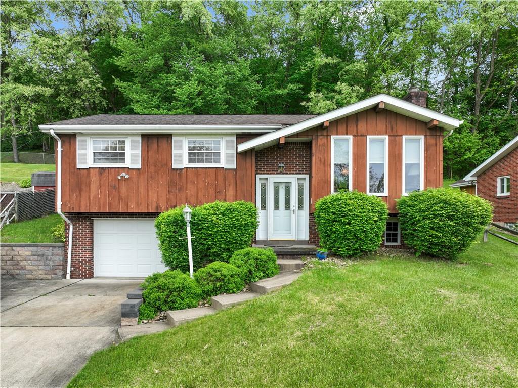 a view of a house with a yard plants and large tree