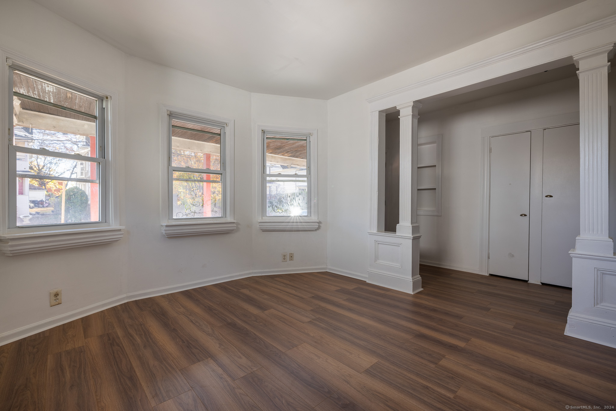 a view of empty room with wooden floor and fan