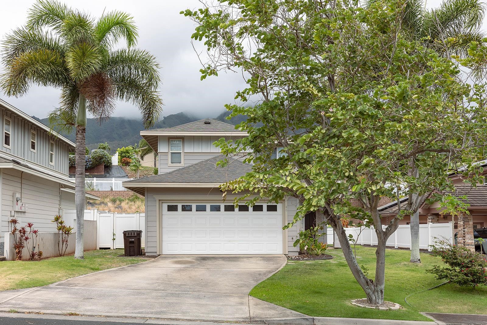 a front view of a house with a garden and tree