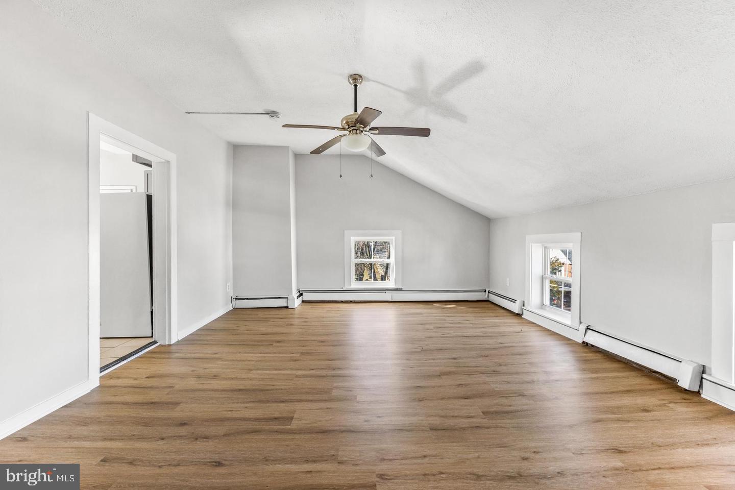 a view of an empty room with window and wooden floor