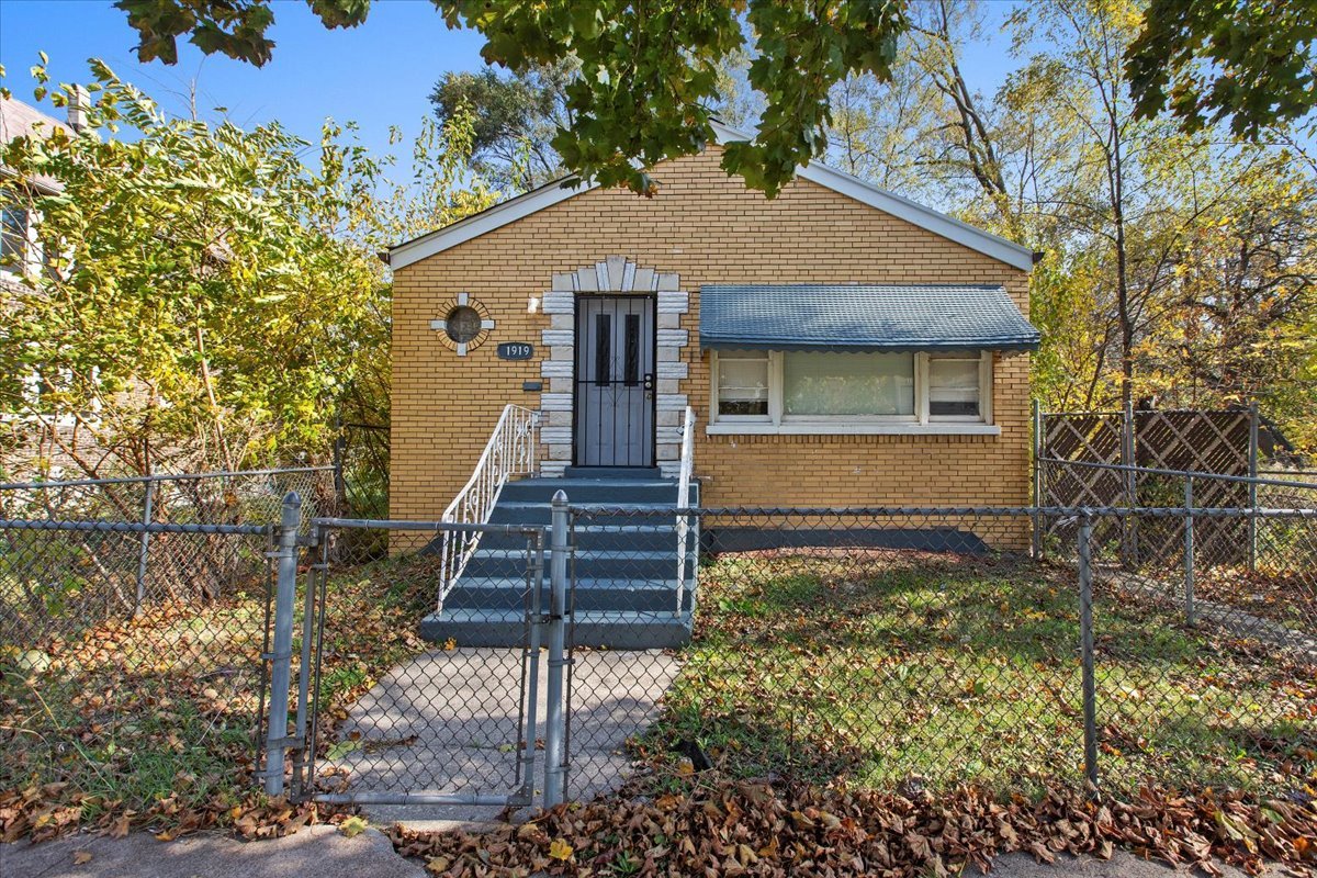 a front view of a house with wooden fence and a tree