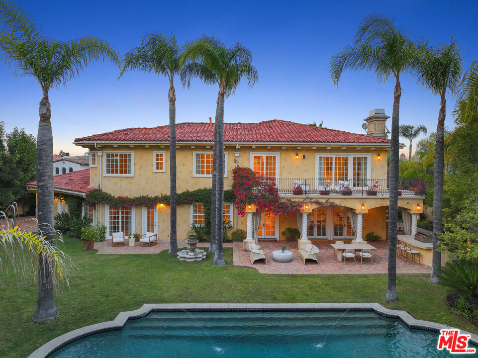 a front view of a house with a garden and lake view