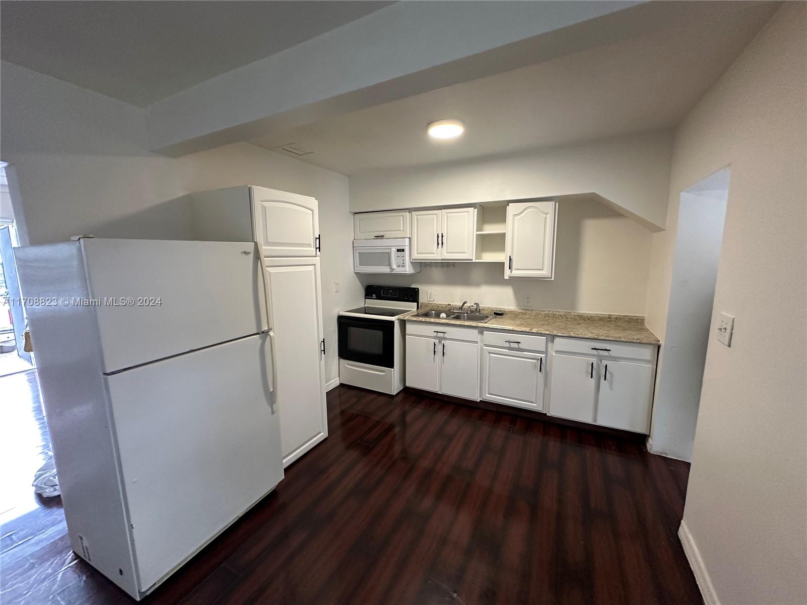 a kitchen with a refrigerator a sink and wooden floor