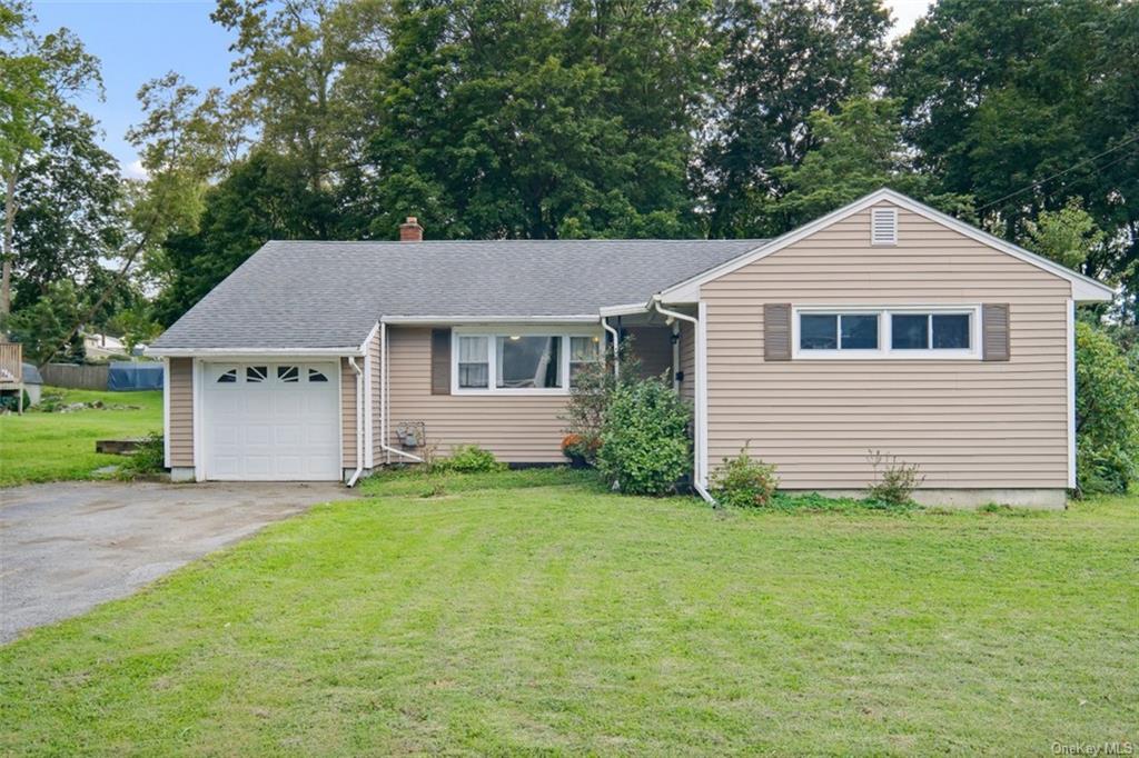 Single story home featuring a garage and a front lawn