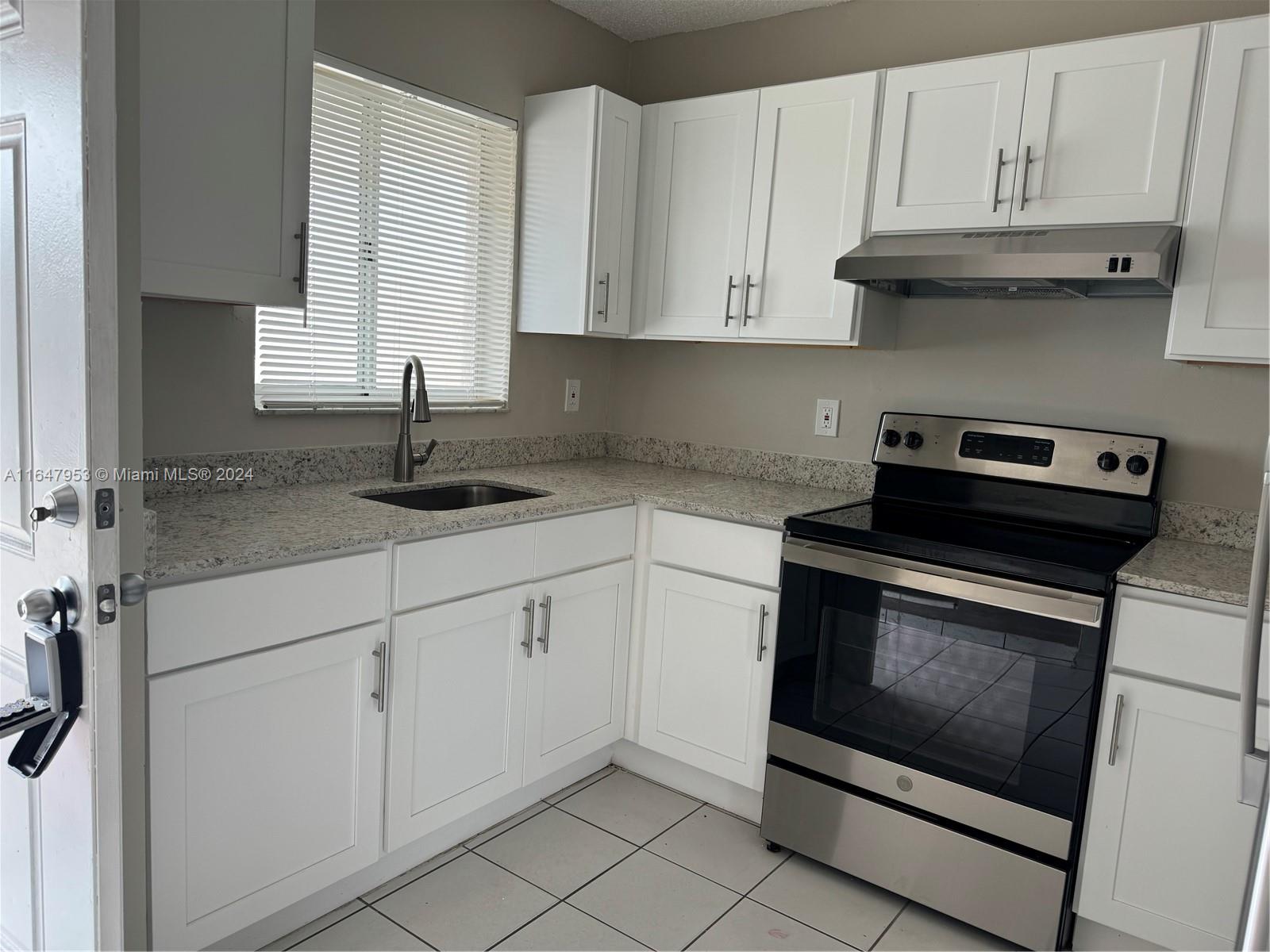 a kitchen with granite countertop white cabinets and a stove