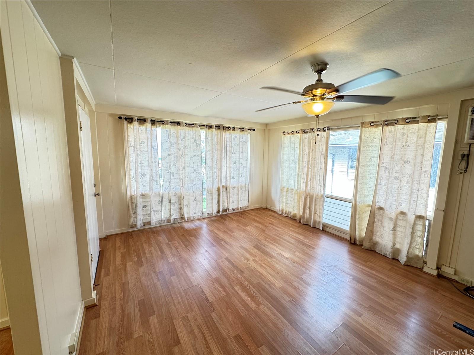 an empty room with wooden floor fan and windows