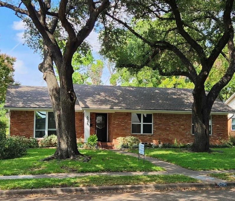 a front view of a house with a garden and trees