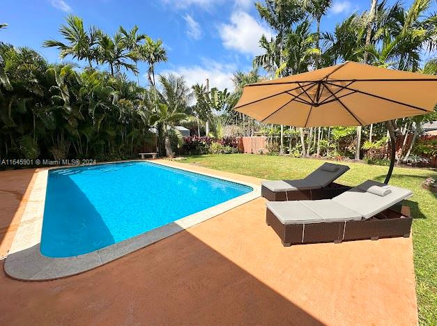 a view of a swimming pool with lawn chairs under an umbrella