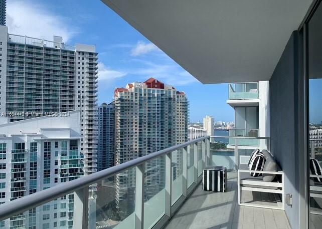 a view of balcony with a couple of cars parked in front of house