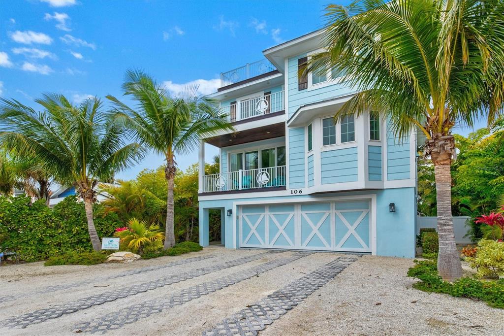 a view of a house with a yard and palm trees