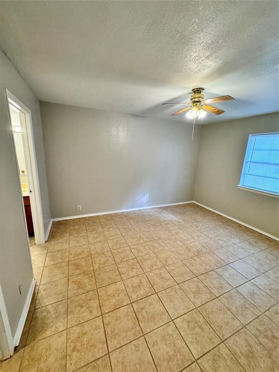 en empty room with windows and ceiling fan