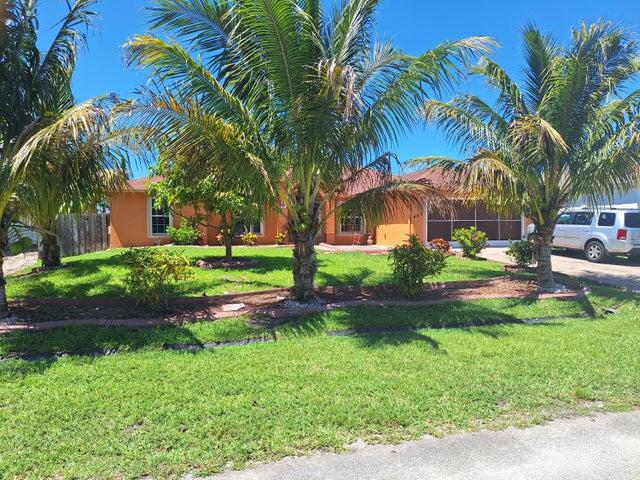 a view of a house with a yard and palm trees