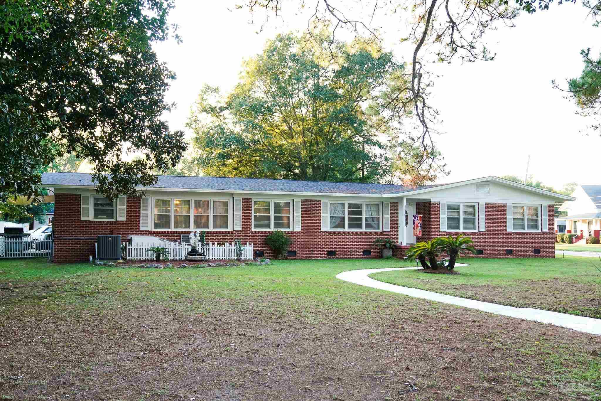 a front view of a house with a garden and trees