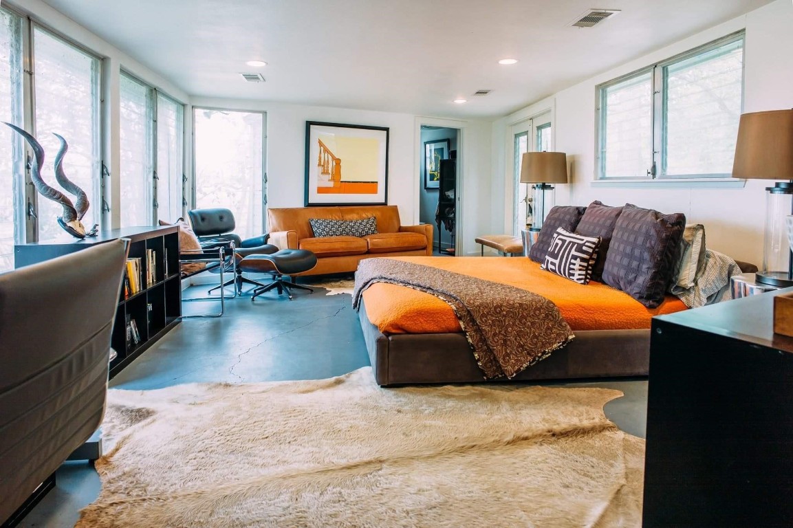 a bedroom with a bed couch and large windows