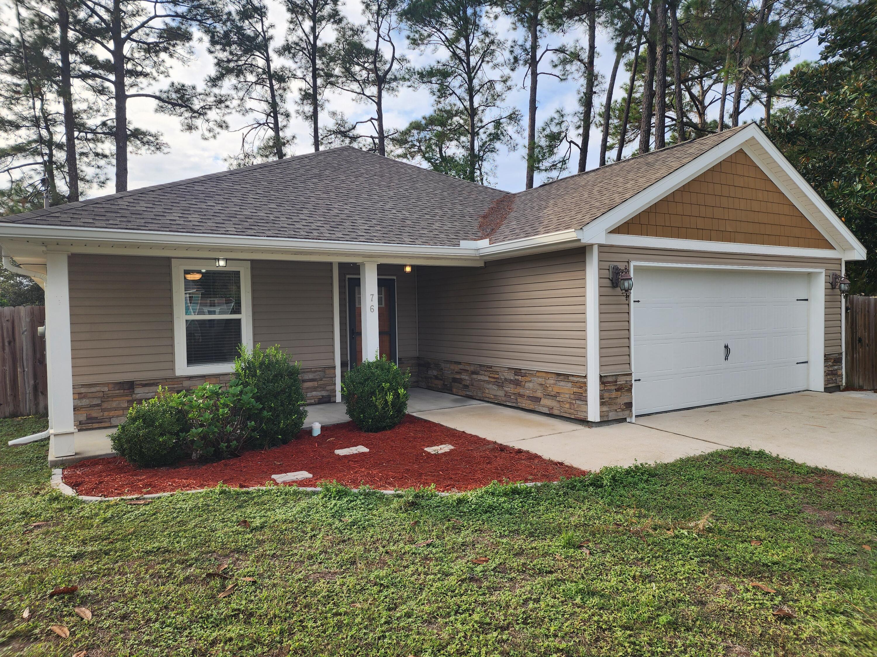 a front view of house with yard and trees in the background