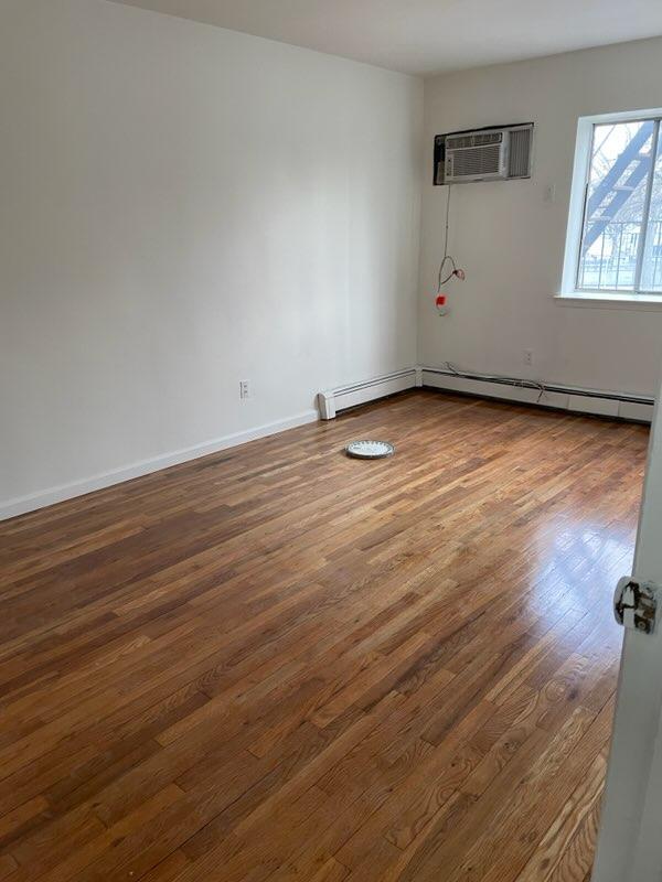 Unfurnished room featuring hardwood / wood-style floors and a wall mounted air conditioner