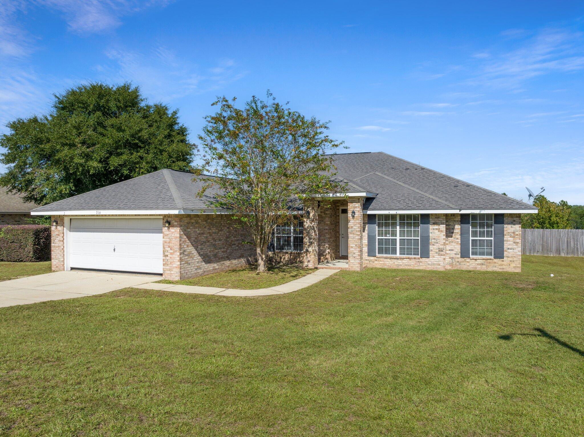 a front view of a house with a yard and trees