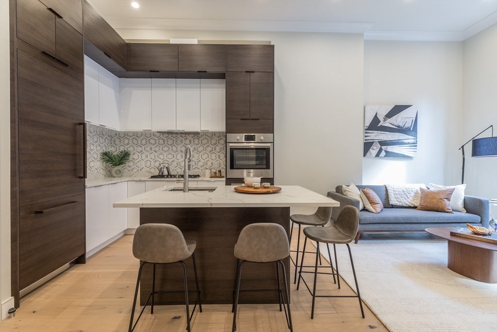 a living room with stainless steel appliances kitchen island granite countertop furniture a rug and a window