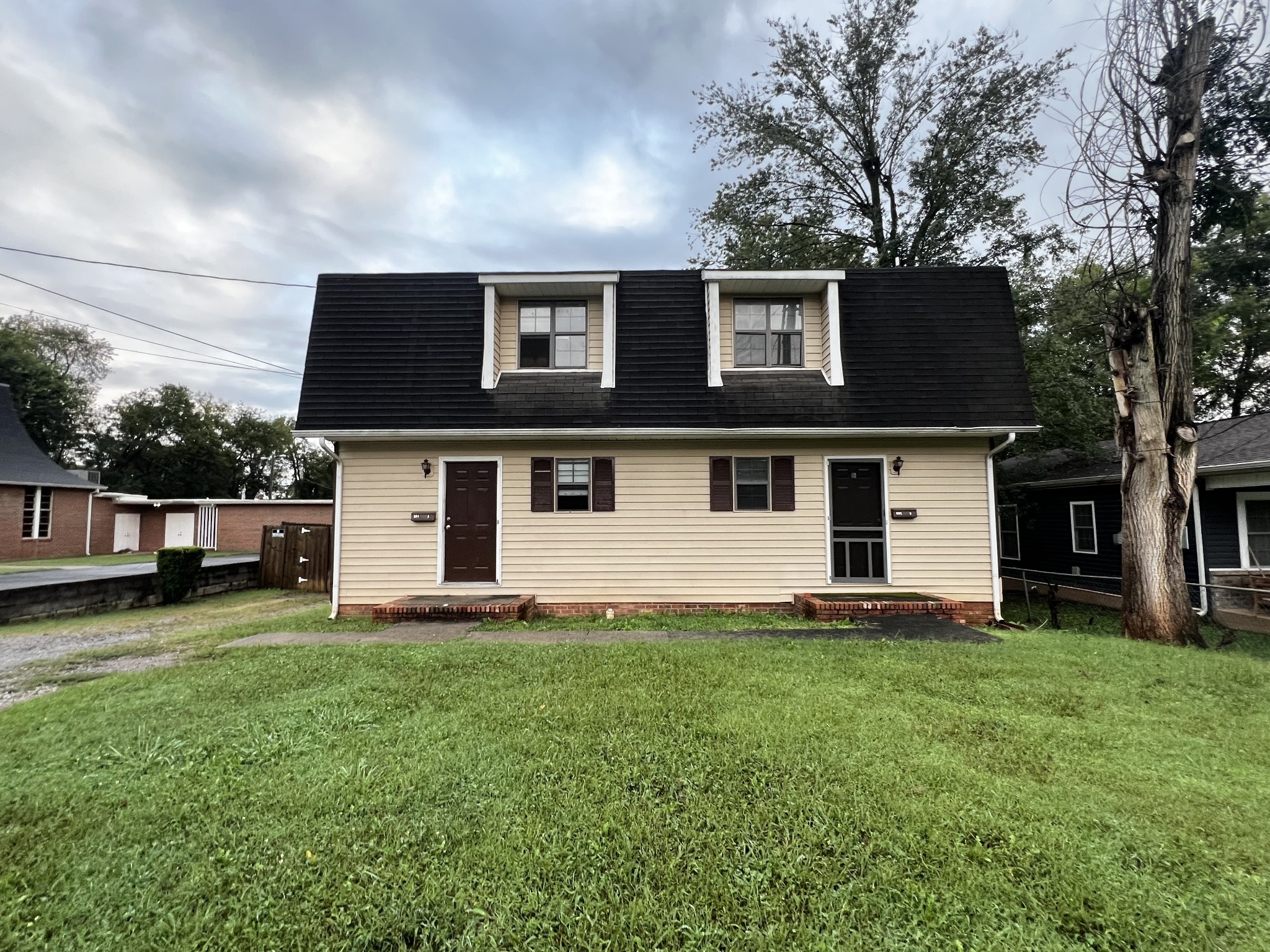 a front view of house with yard and trees in the background