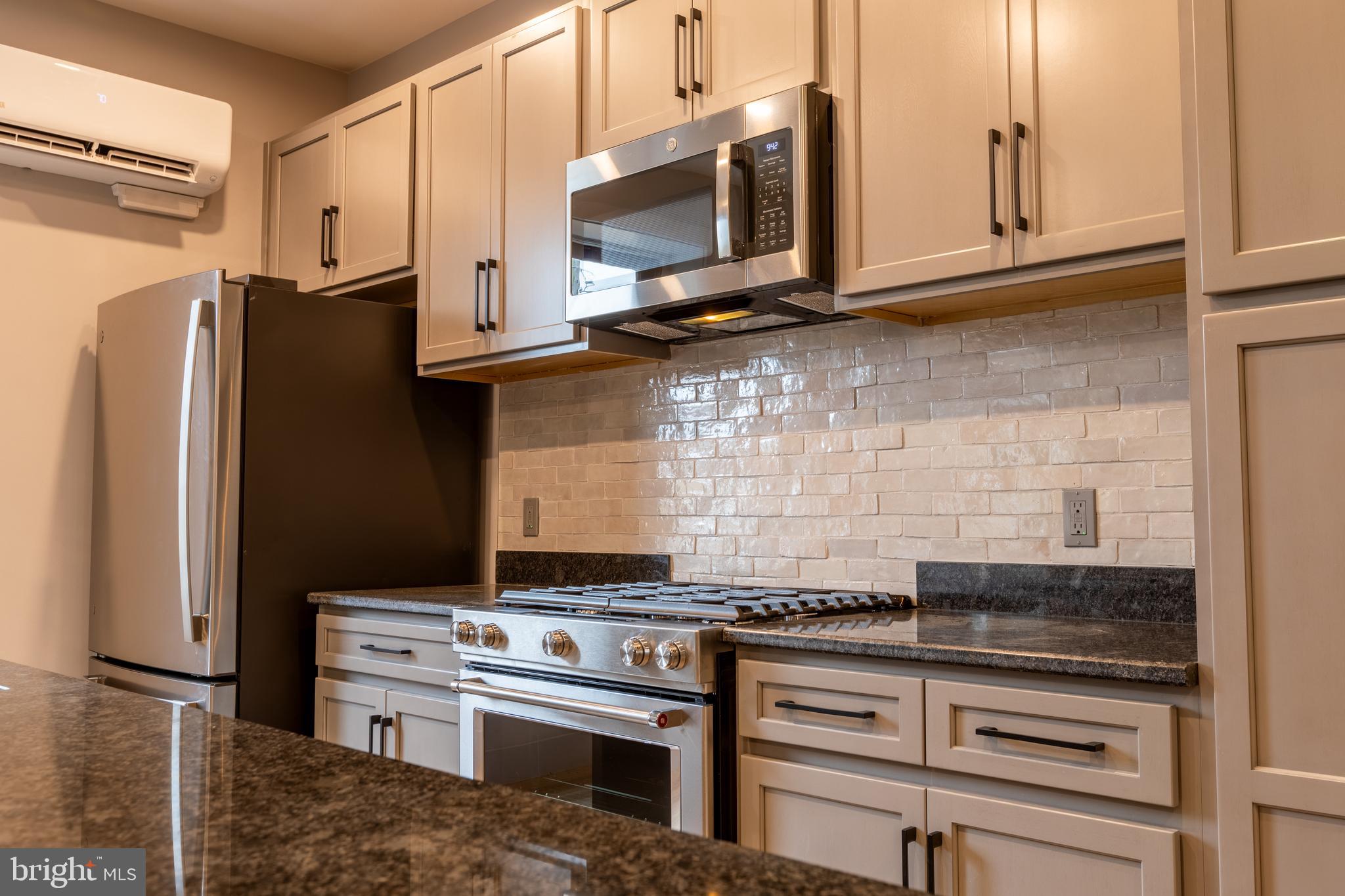 a kitchen with stainless steel appliances granite countertop a stove microwave and refrigerator